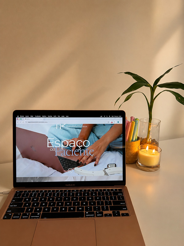 Notebook aberto no Espaço do Paciente, ao lado de uma vela e uma planta